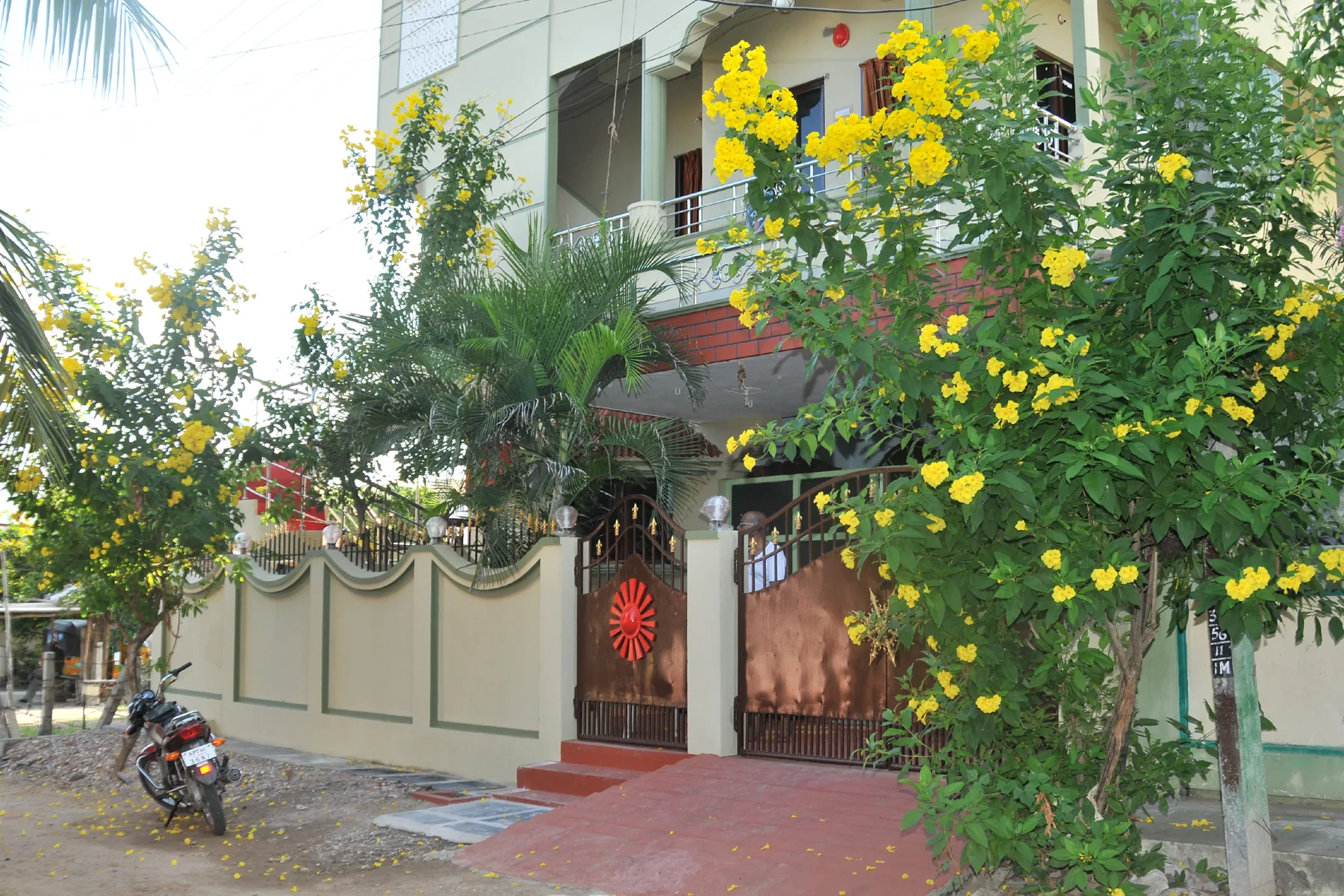 Entrance gate and flowering trees at the AYTAS Guntur hub.